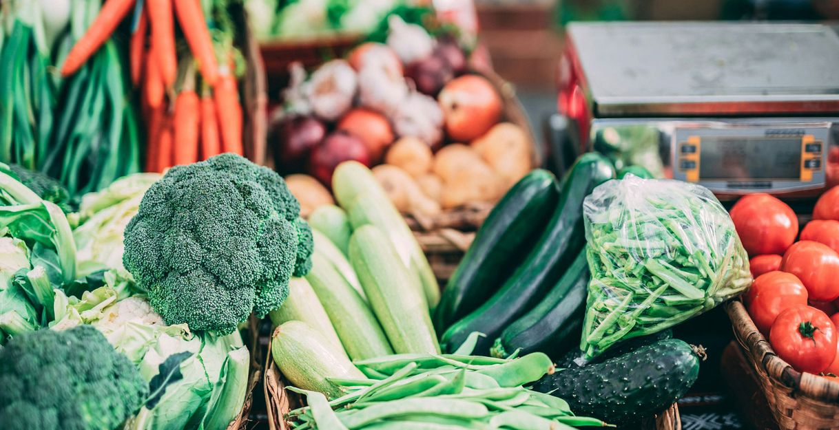 Frisches Gemüse auf einem Wochenmarkt, darunter Brokkoli, Karotten, Zucchini und Tomaten.