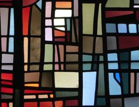Buntes Kirchenfenster mit abstraktem Design aus verschiedenen farbigen Glasstücken.